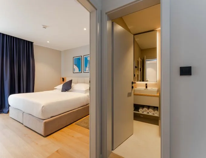 Espacio representativo del hotel: Un dormitorio con una cama junto al lavabo abierto del baño.