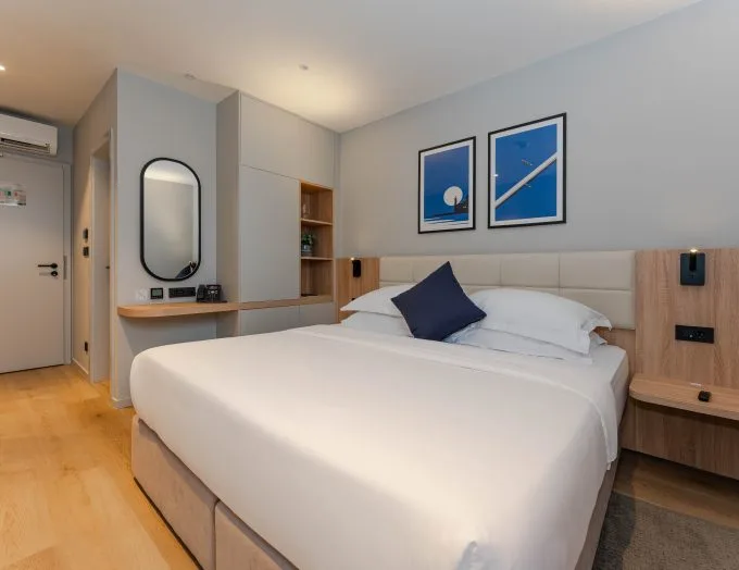 Espacio representativo del hotel: Un dormitorio de hotel luminoso con una cama tendida y cuadros azules.