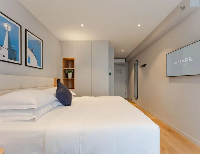 Espacio representativo del hotel: Un dormitorio con una cama bien tendida y cuadros enmarcados en la pared.