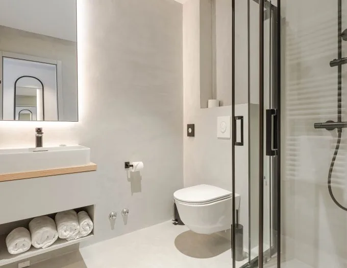 Espacio representativo del hotel: Un baño luminoso con lavabo, inodoro suspendido y ducha de vidrio.