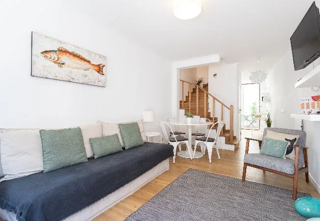 A bright living room with a long sofa and a small dining table.