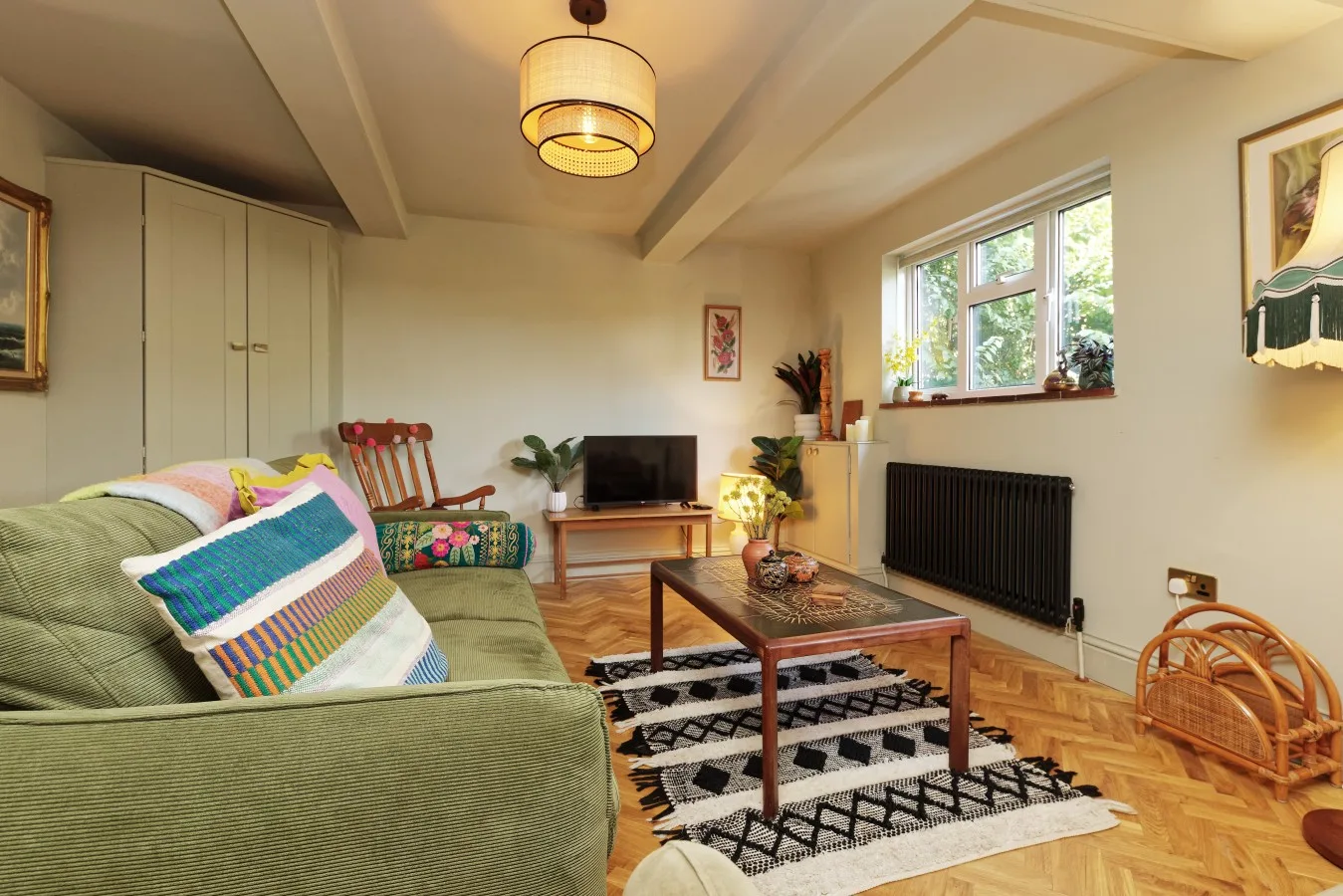 A living room with seating, a coffee table, and a television beneath a window.