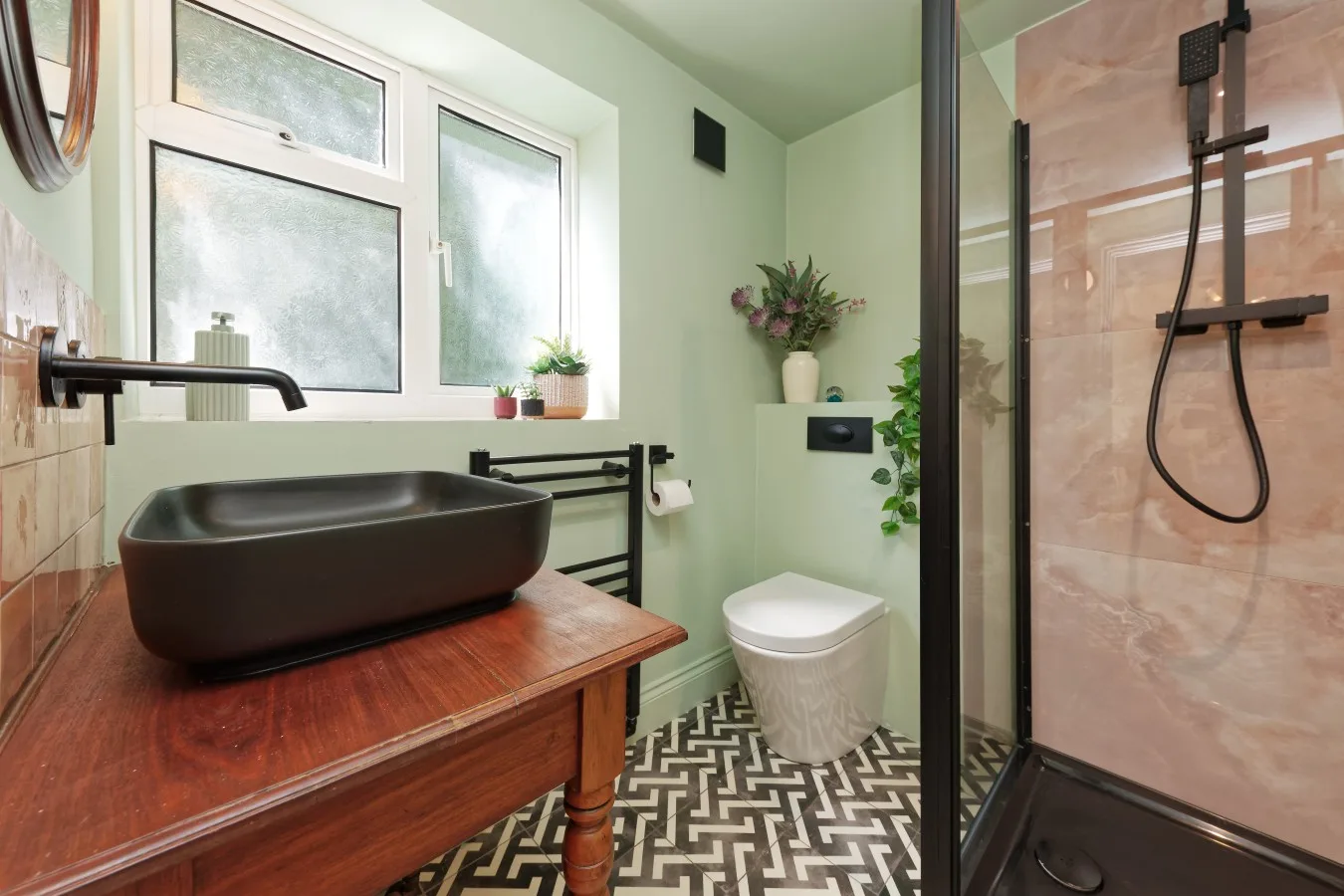 A bathroom with a dark basin on a wooden vanity beside a shower.