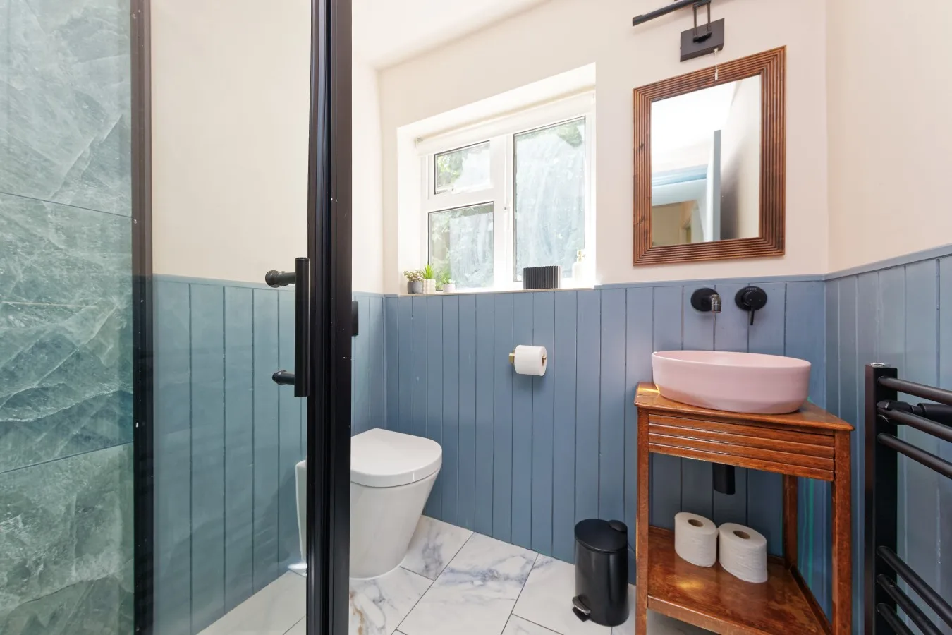 A bathroom with a glass shower, toilet, and sink on a wooden vanity.