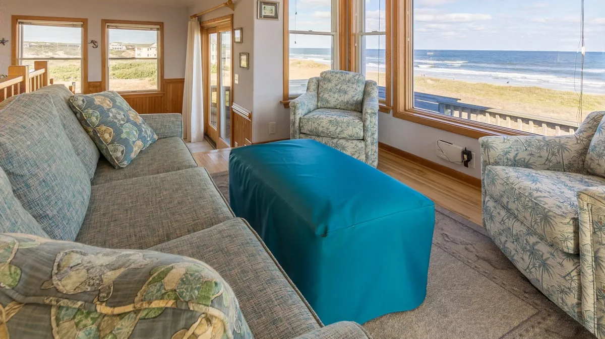 Una sala de estar con asientos y una ventana grande con vista a la playa.