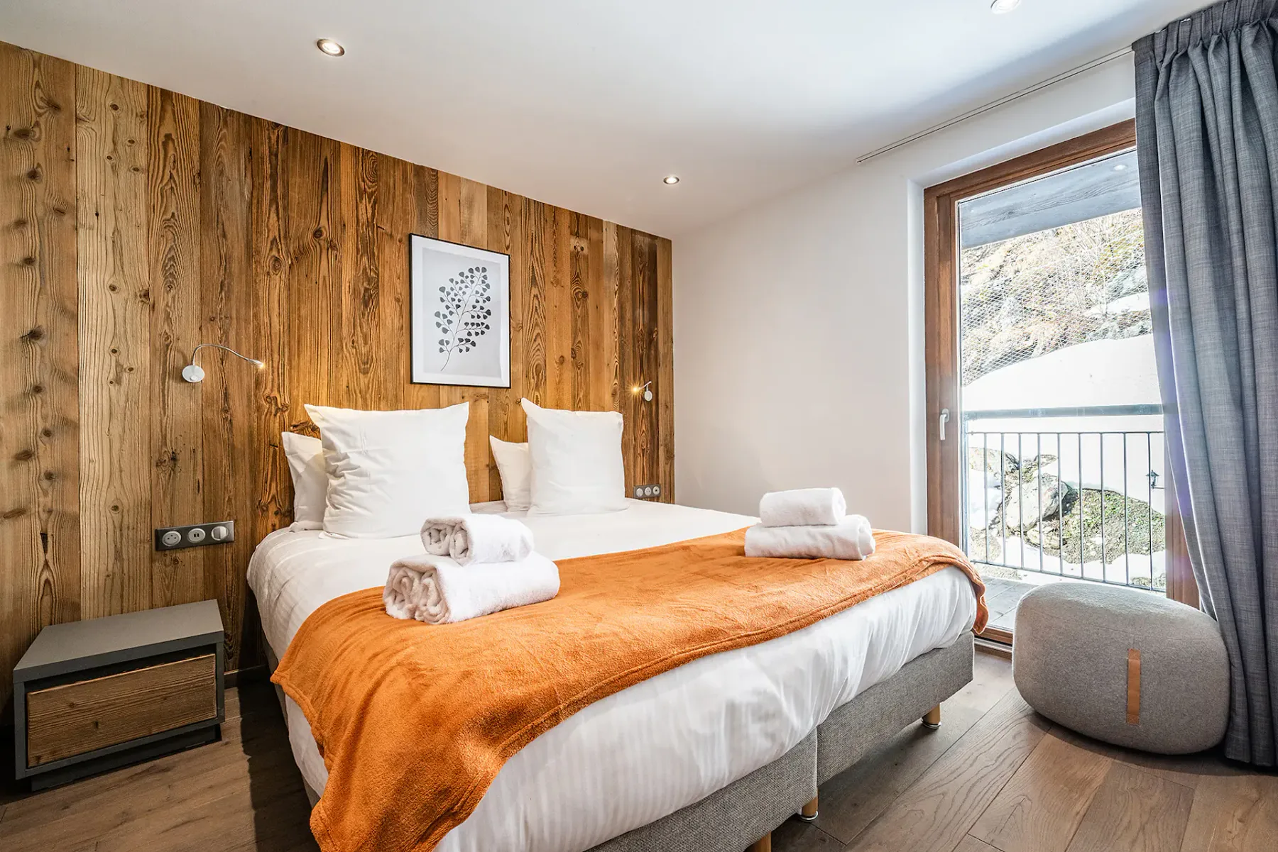 Un dormitorio con una cama vestida con sábanas blancas y una manta naranja.