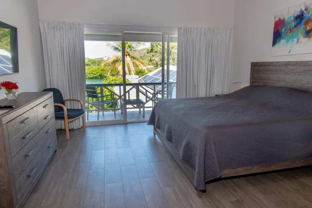 Espacio representativo del hotel: Un dormitorio con una cama grande y puertas corredizas de vidrio que dan a un balcón.