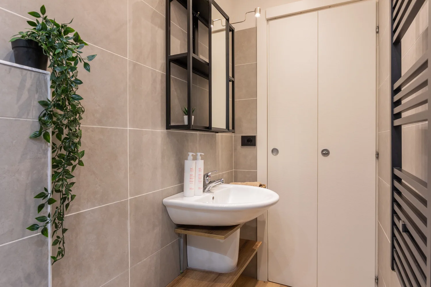 A bathroom with a wall-mounted sink and tiled walls.