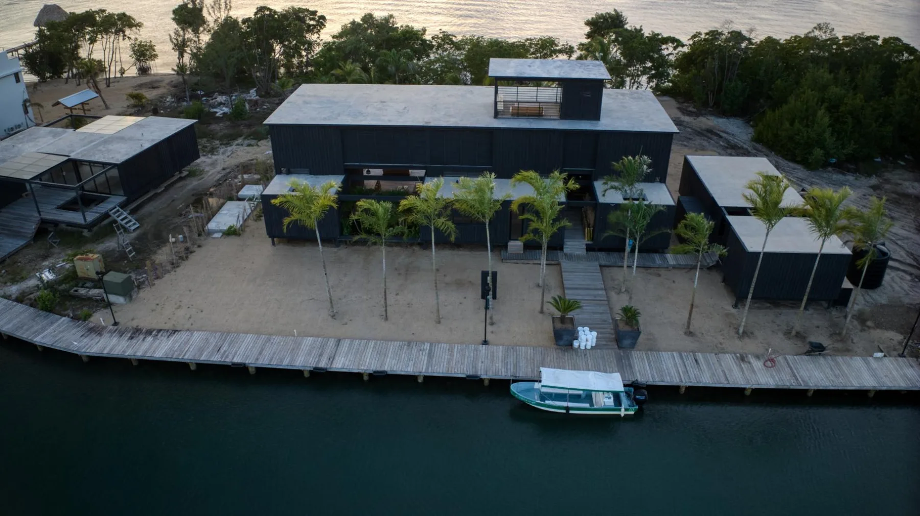 Vista aérea de un edificio junto al agua, con un muelle y una embarcación.