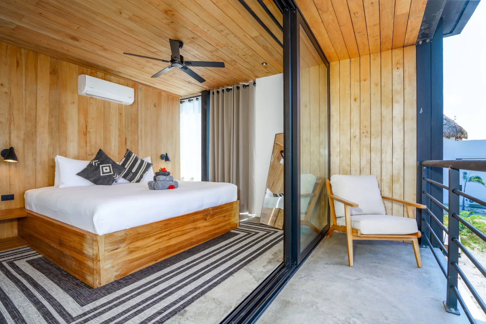 Un dormitorio revestido de madera se abre a un balcón con un asiento acolchado.