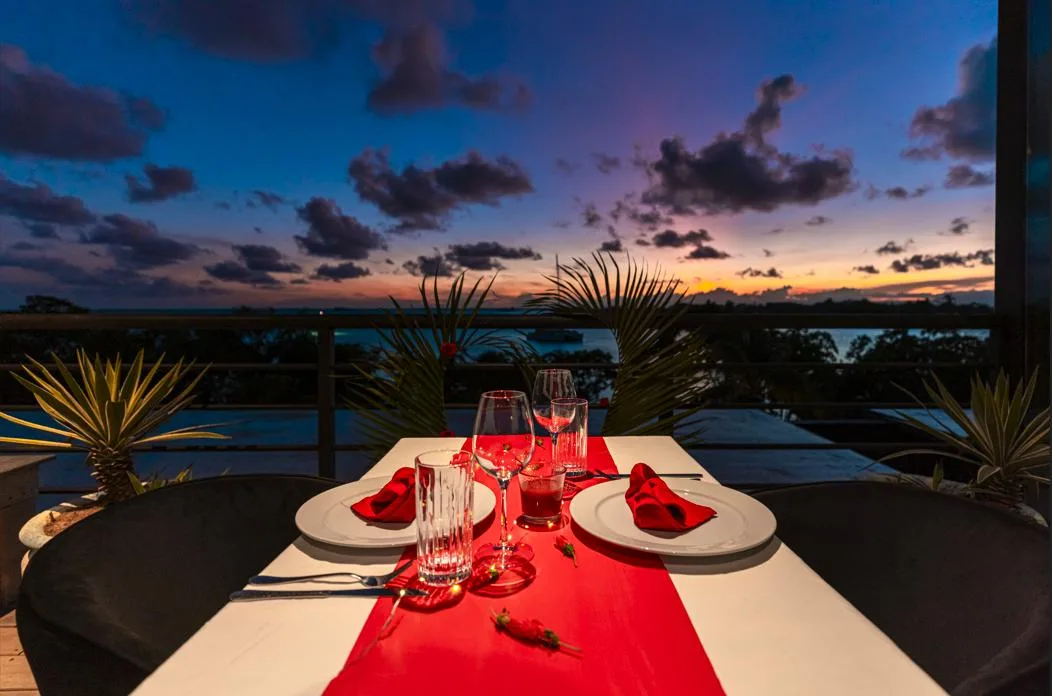Una mesa de comedor al aire libre con un camino rojo mira hacia el cielo al atardecer.