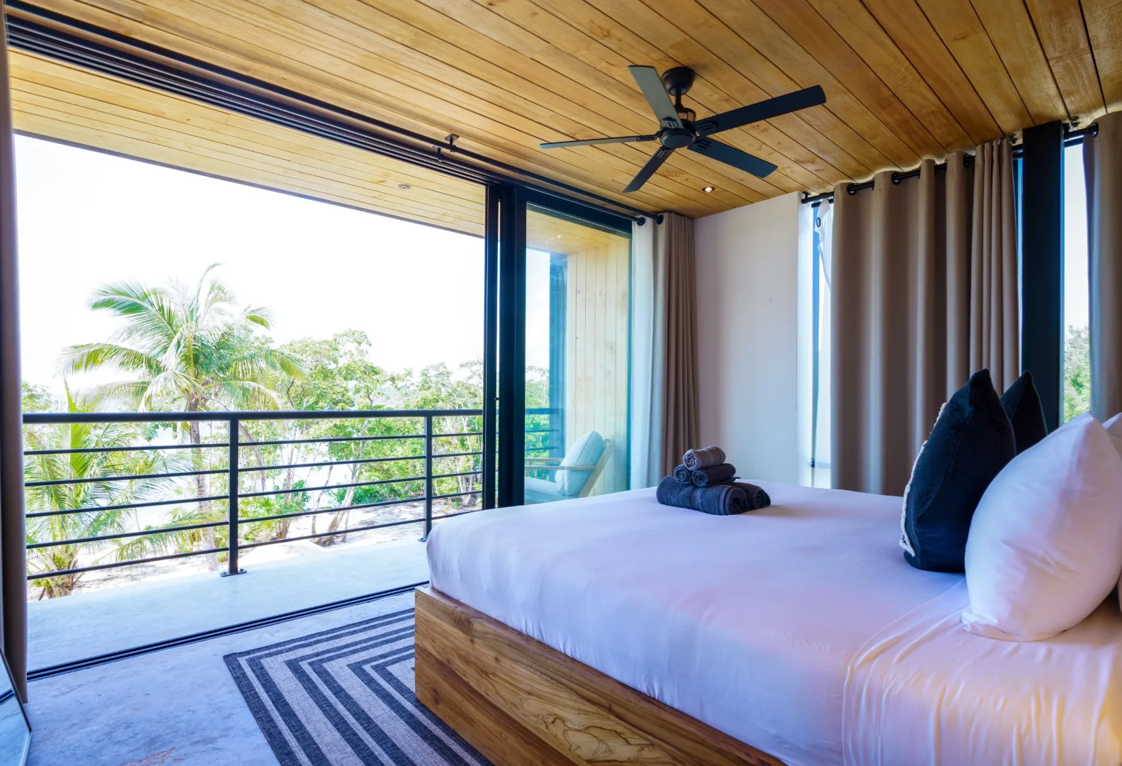 Un dormitorio con una cama junto a amplias puertas corredizas de vidrio que dan a un balcón.