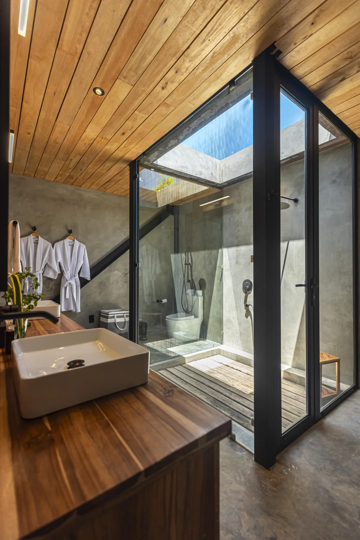 Un baño con una ducha acristalada bajo un techo de madera.