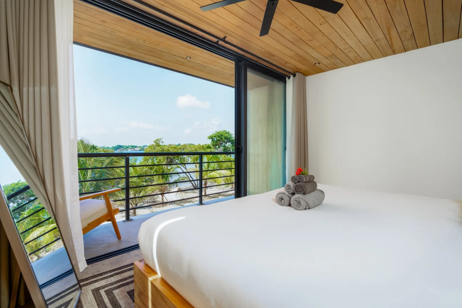 Un dormitorio con una cama grande junto a puertas corredizas de vidrio que dan a un balcón.