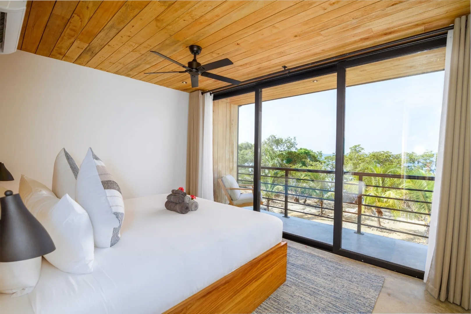 Un dormitorio con una cama junto a grandes puertas de vidrio que dan a un balcón.