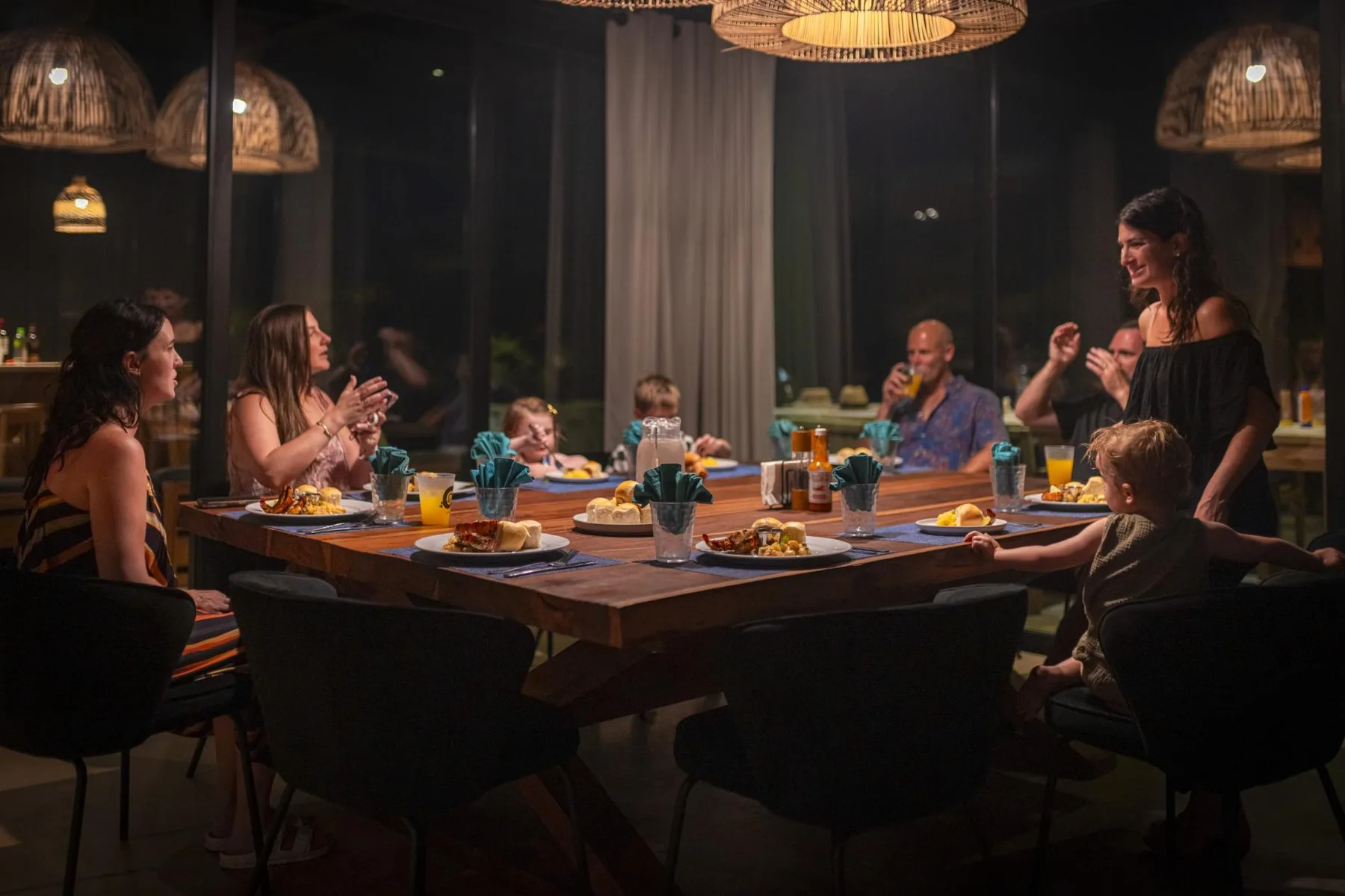 Un grupo se reúne alrededor de una mesa puesta con comida y bebidas.