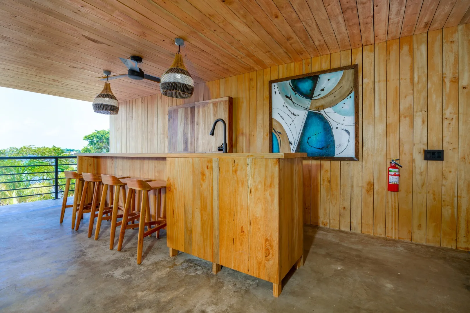 Una cocina revestida de madera con barra, taburetes y una obra enmarcada.