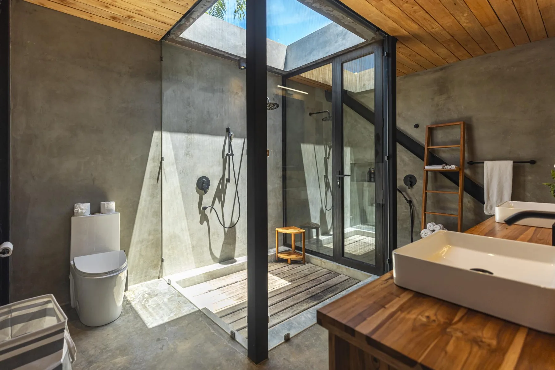 Un baño moderno con ducha de vidrio, inodoro y tocador de madera.