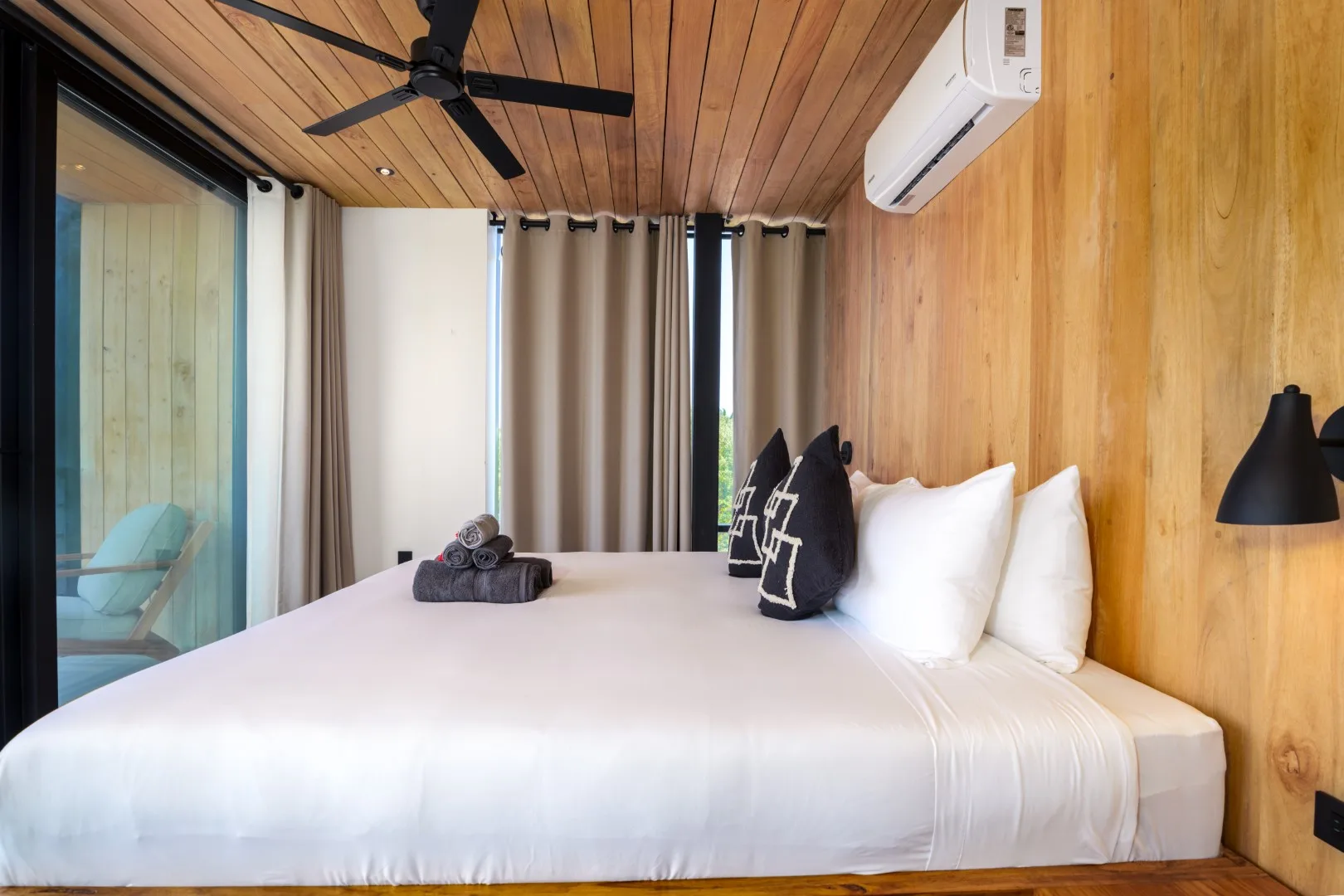 Un dormitorio con una cama grande, paredes revestidas de madera y cortinas.