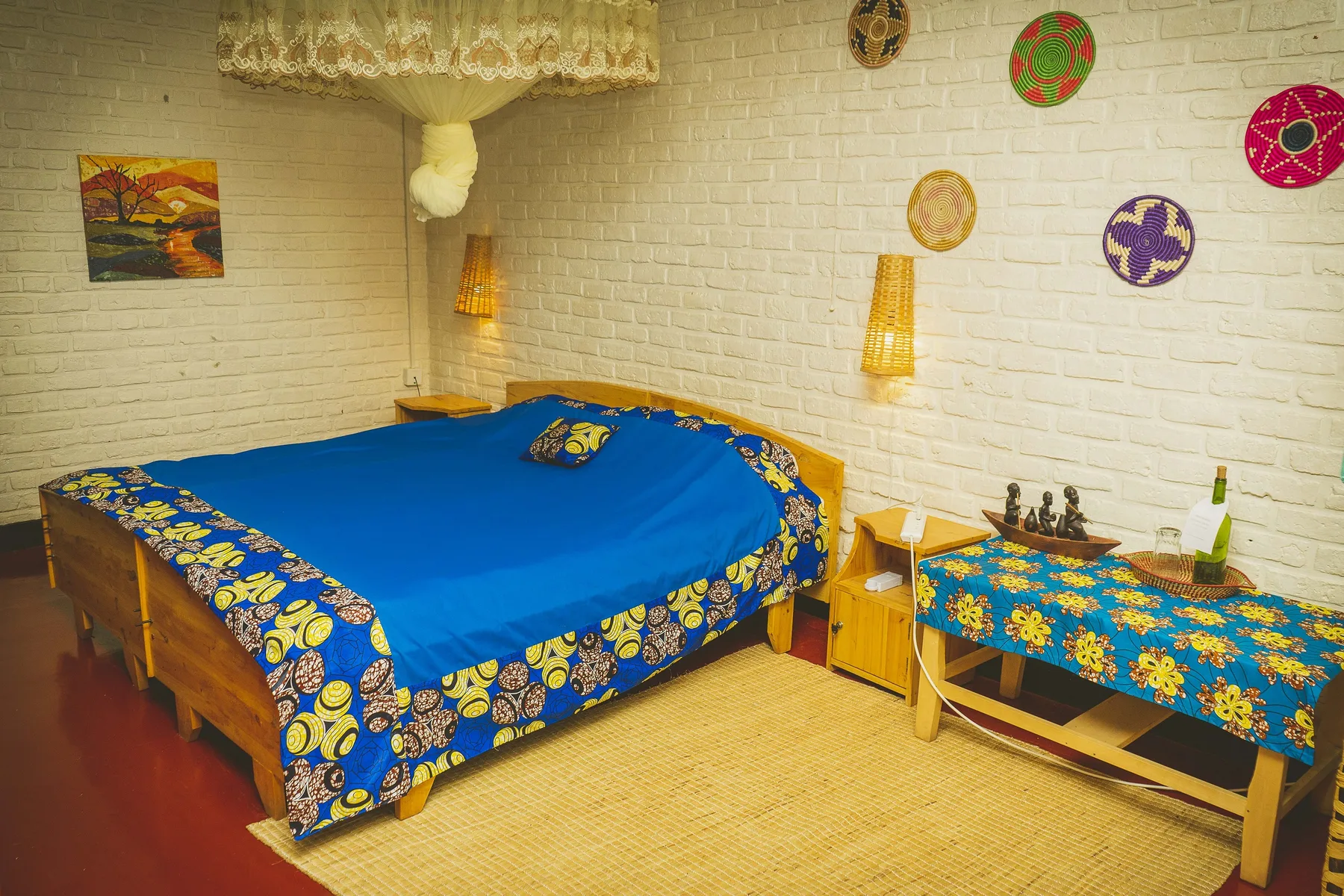 Espacio representativo del hotel: Dormitorio con una cama cubierta de azul y adornos coloridos en la pared.