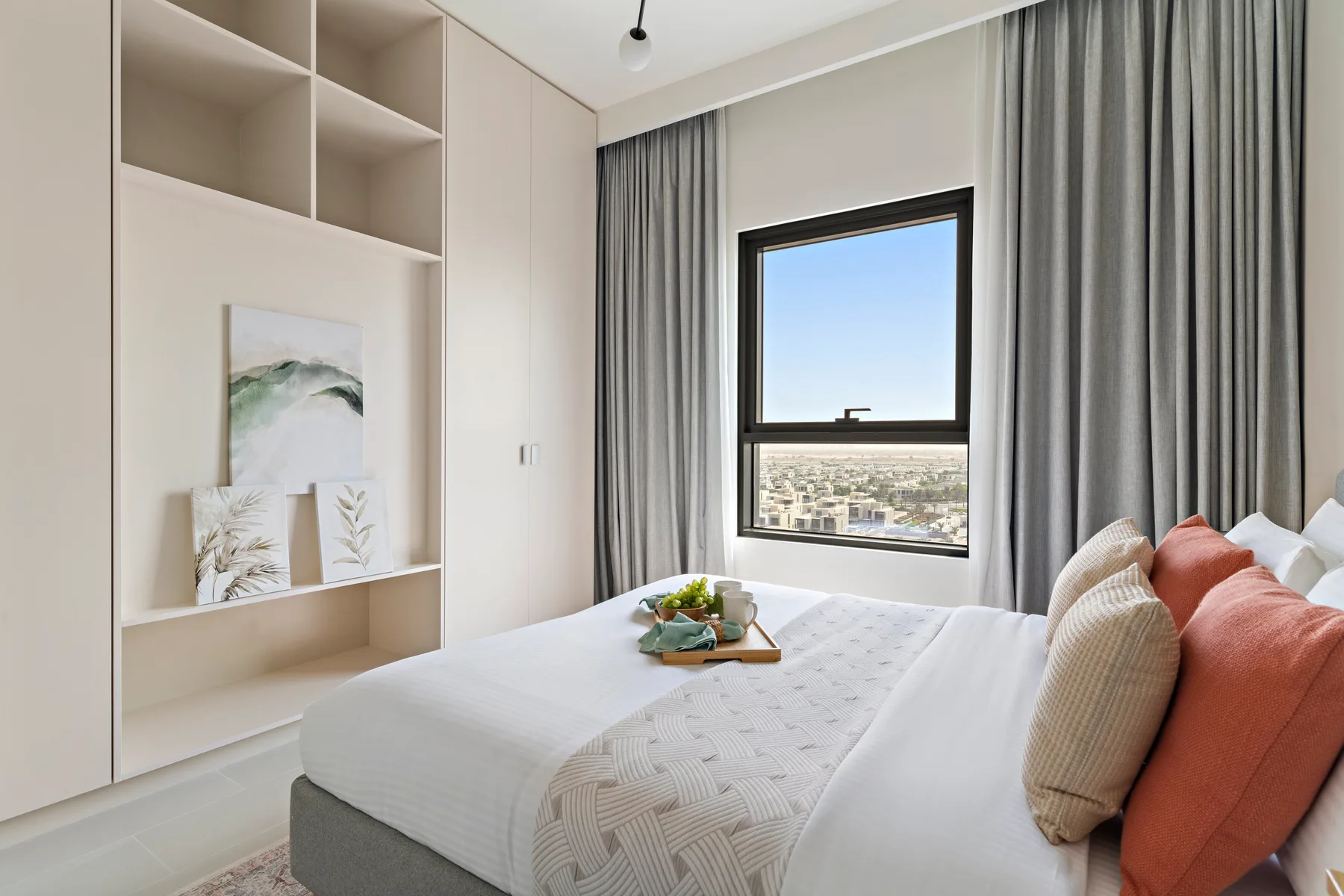Un dormitorio con una cama junto a una ventana con cortinas grises.
