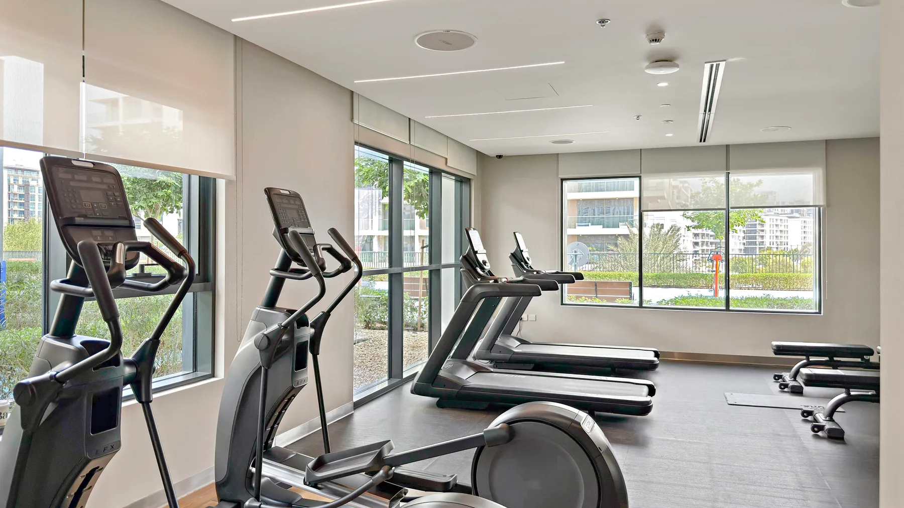 Zona común: Un gimnasio con máquinas de ejercicio junto a grandes ventanas.