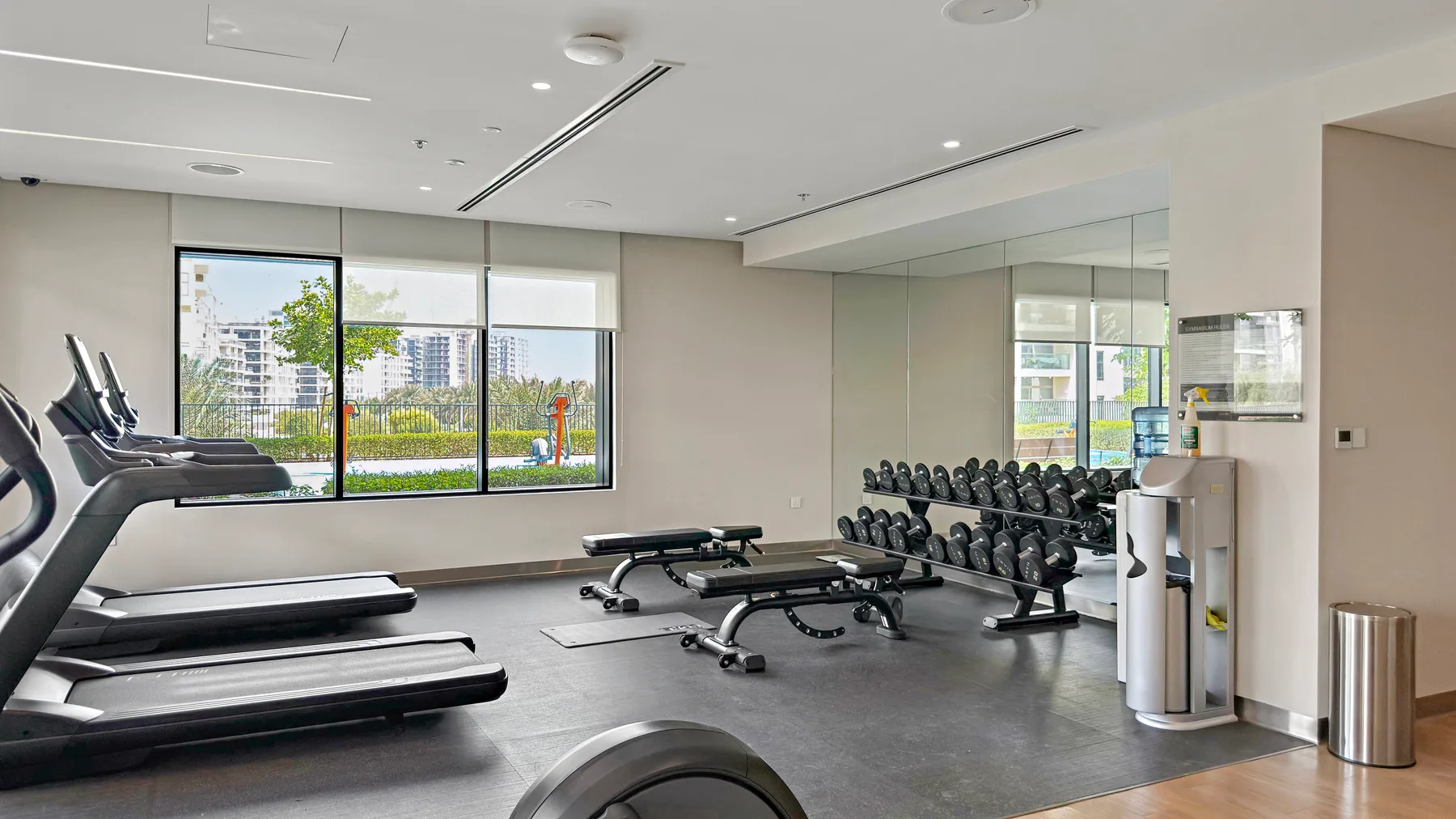 Zona común: Un gimnasio con cintas de correr, bancos de pesas y una fila de mancuernas.