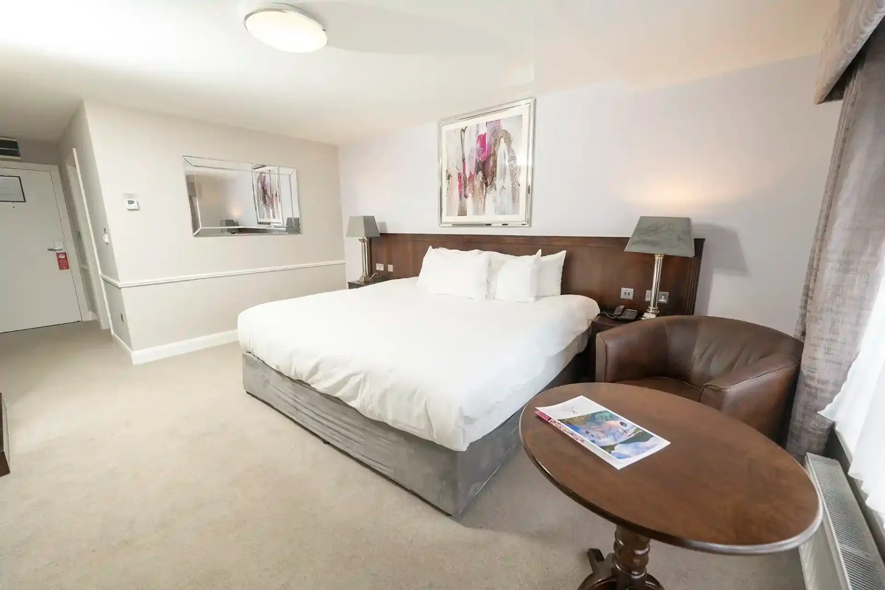 Representative hotel space: A hotel bedroom with a large bed and seating beside a window.