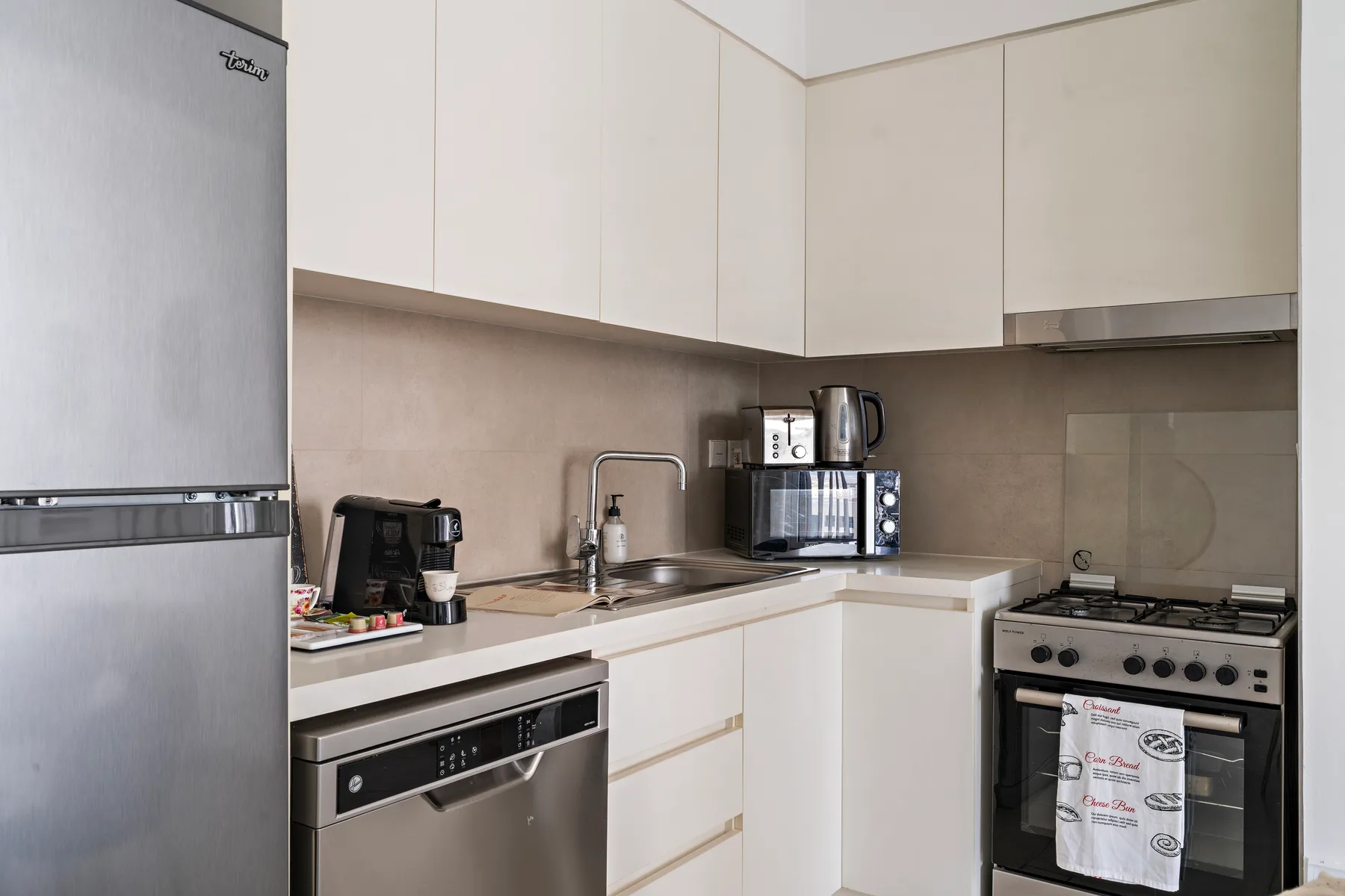 Una cocina luminosa con armarios blancos, una encimera y electrodomésticos.