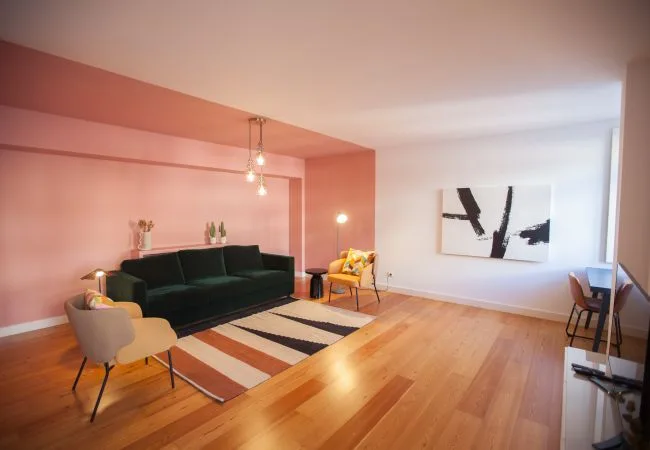 Sala de estar con asientos, una alfombra a rayas y arte abstracto en la pared.