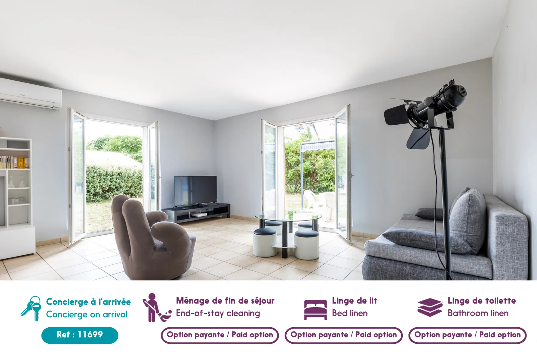 A bright living room with seating, a television, and open doors to a garden.