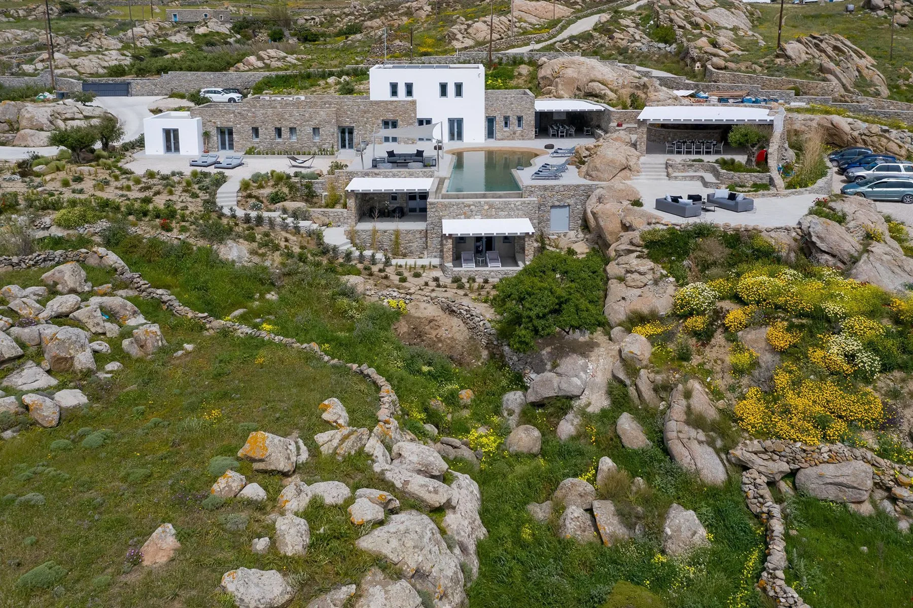 A modern stone-and-white building complex sits among rocky terrain and green vegetation.