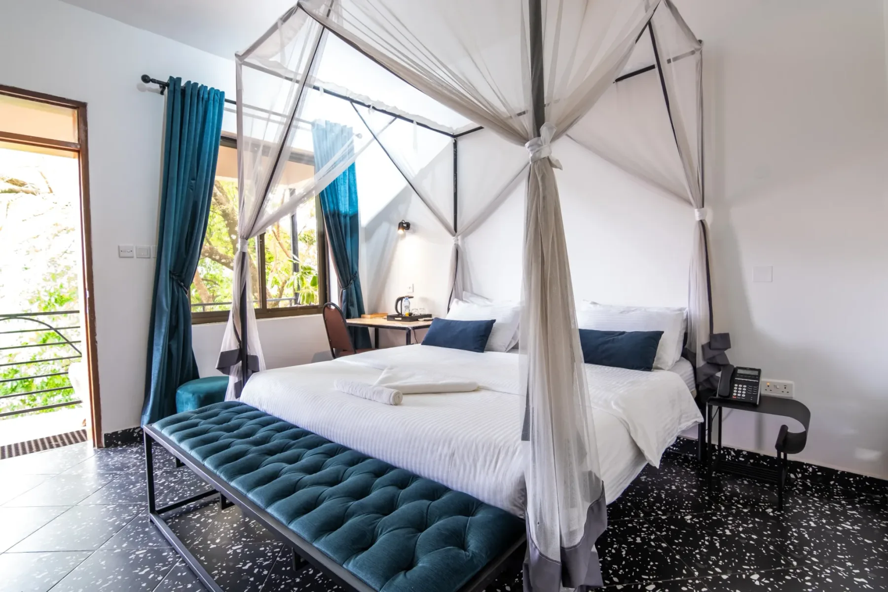 Representative hotel space: A bedroom with a canopy bed and teal curtains beside the windows.