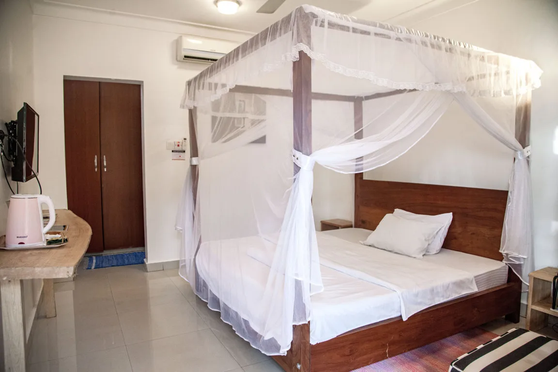 Representative hotel space: A bedroom with a wooden bed surrounded by a white mosquito net.