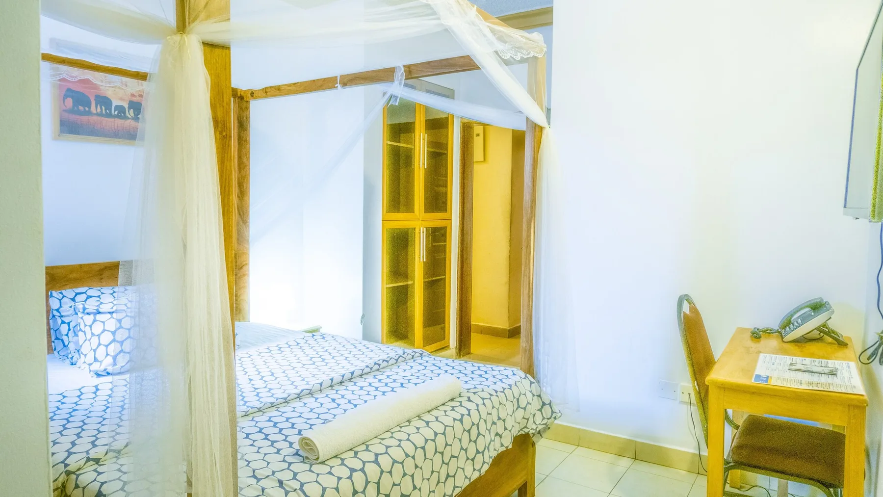 Representative hotel space: A bedroom with a patterned bed beside a small desk.