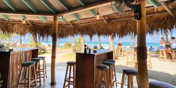 Espacio representativo del hotel: Un bar junto a la playa, con taburetes, da al océano.