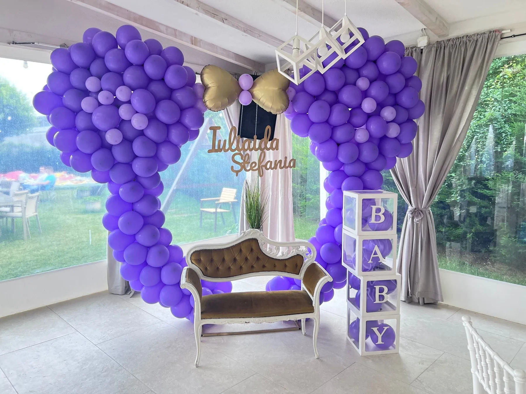 Espacio representativo del hotel: Un espacio decorado para eventos presenta arreglos de globos morados y un pequeño sofá.