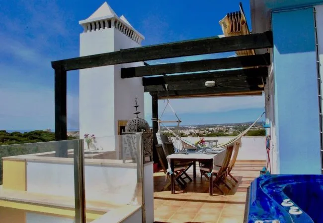 Una terraza en la azotea con mesa de comedor, hamaca y vistas al paisaje.