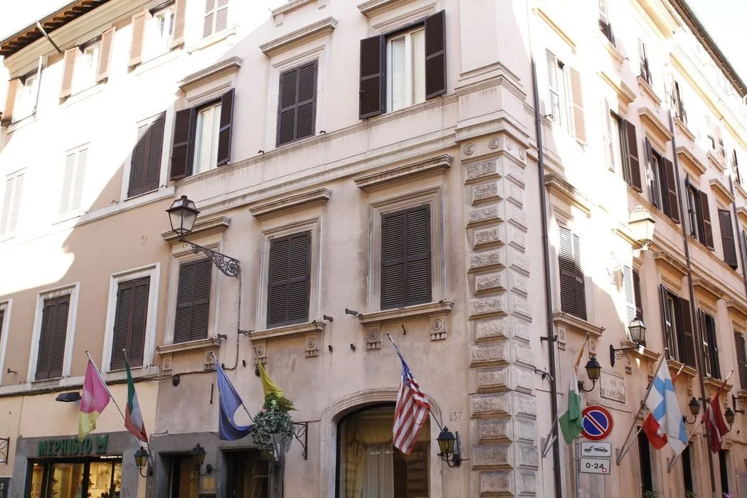 Espacio representativo del hotel: Vista de la calle con un edificio de varias plantas, ventanas con contraventanas y banderas.