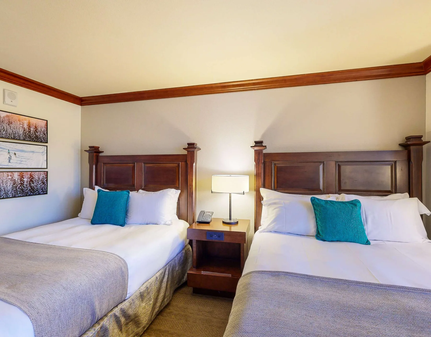 Bedroom with two beds, bedside table, and a lamp between them.