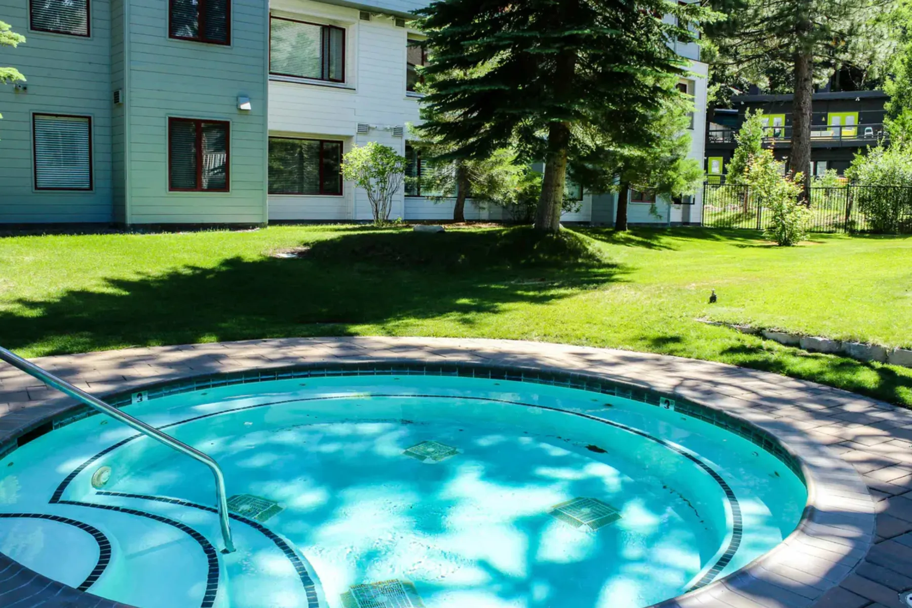 Shared amenity: An outdoor swimming pool sits beside a lawn and modern buildings.