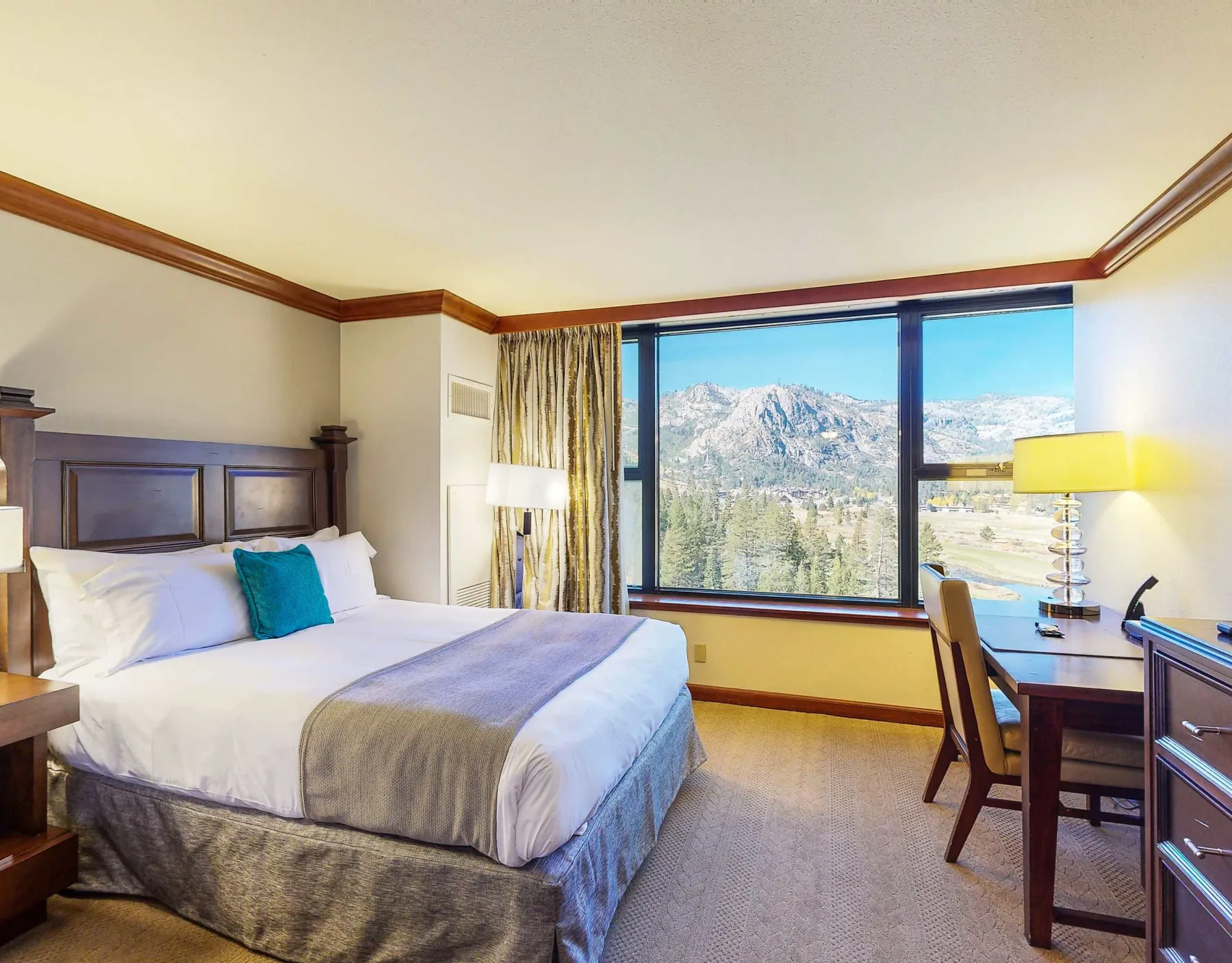 A bedroom with a large window overlooking a mountain landscape.