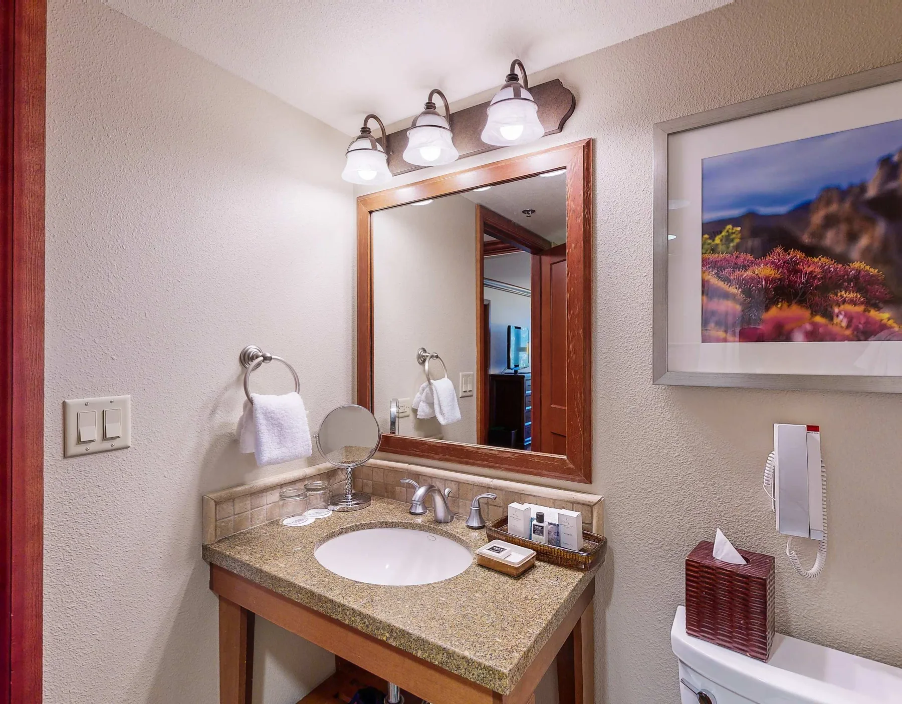 A bathroom vanity with a sink, mirror, and wall-mounted lights.