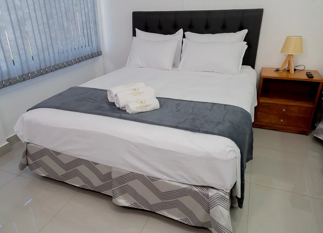 Espacio representativo del hotel: Un dormitorio con una cama bien tendida y una mesa de noche.