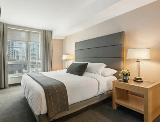Espacio representativo del hotel: Un dormitorio de hotel con una cama grande, mesas de noche y una ventana.