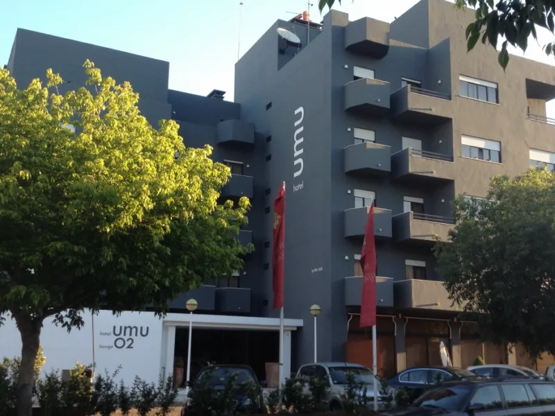 Espacio representativo del hotel: Exterior de hotel moderno con balcones, árboles y coches estacionados.