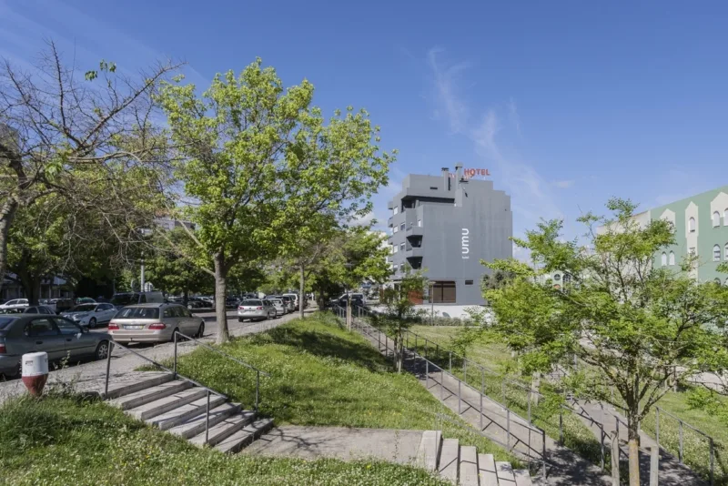 Espacio representativo del hotel: Exterior del hotel junto a una pendiente ajardinada y una zona de estacionamiento.