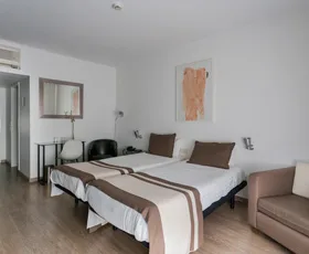 Espacio representativo del hotel: Un dormitorio de hotel con dos camas y una pequeña zona de estar.