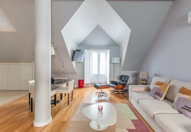 Una luminosa sala de estar con una zona de asientos y una gran ventana central.