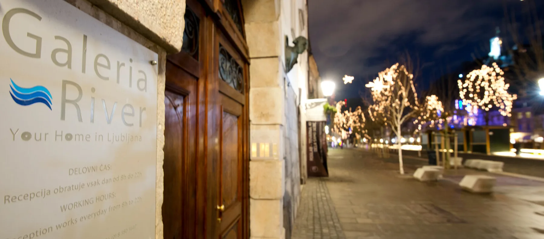 Representative hotel space: A hotel entrance opens onto a nighttime plaza with illuminated trees.